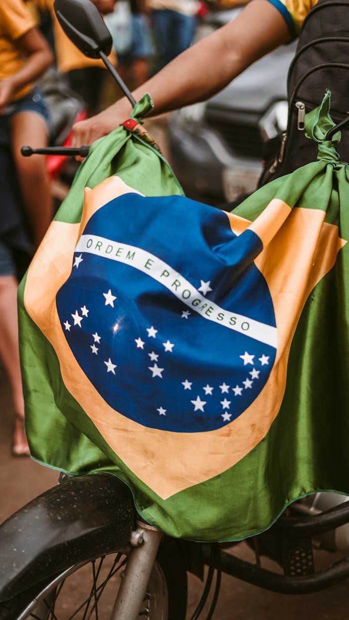 Close-up of a motorcycle adorned with the Brazilian flag during a street gathering.