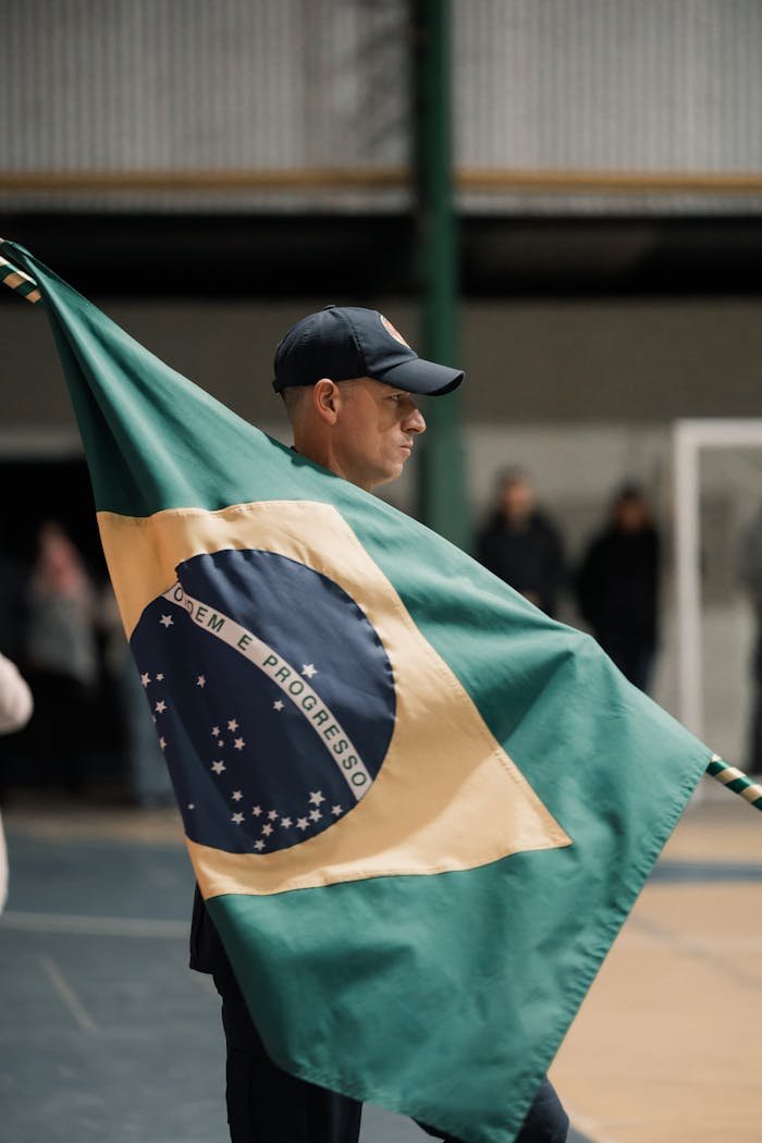 services-03 Man holding a Brazilian flag indoors in a gym-like environment.